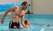 baby swiming aided by one hand