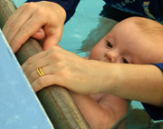 Baby holding side of pool