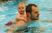 baby swimming on back of dad